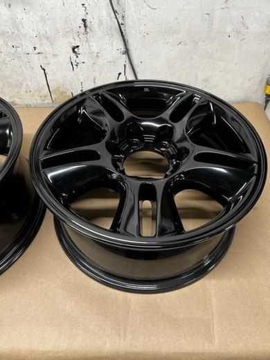 A pair of powder coated black wheels are sitting on a table