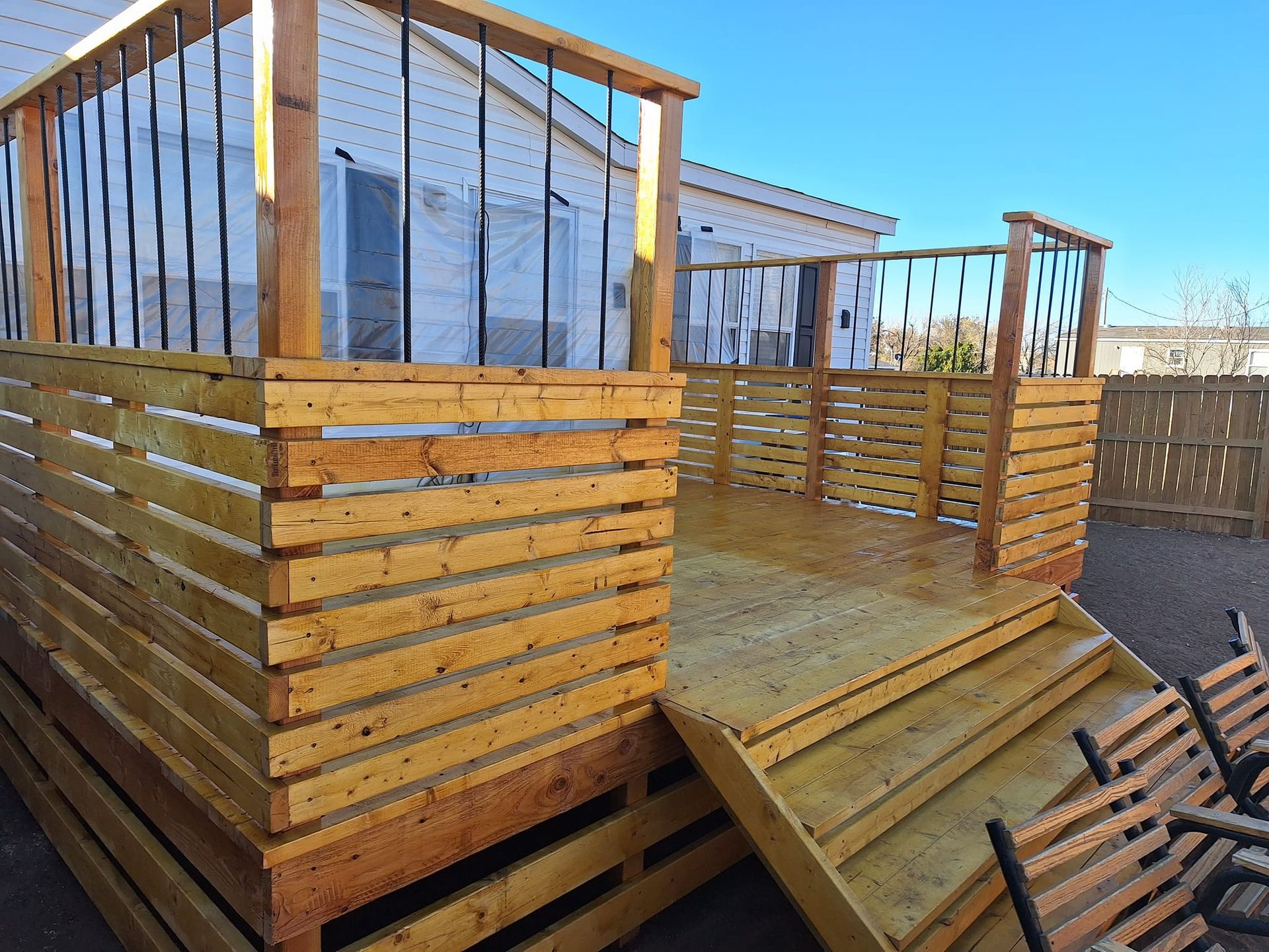 Wooden deck with steps and horizontal plank privacy walls; sunny day.