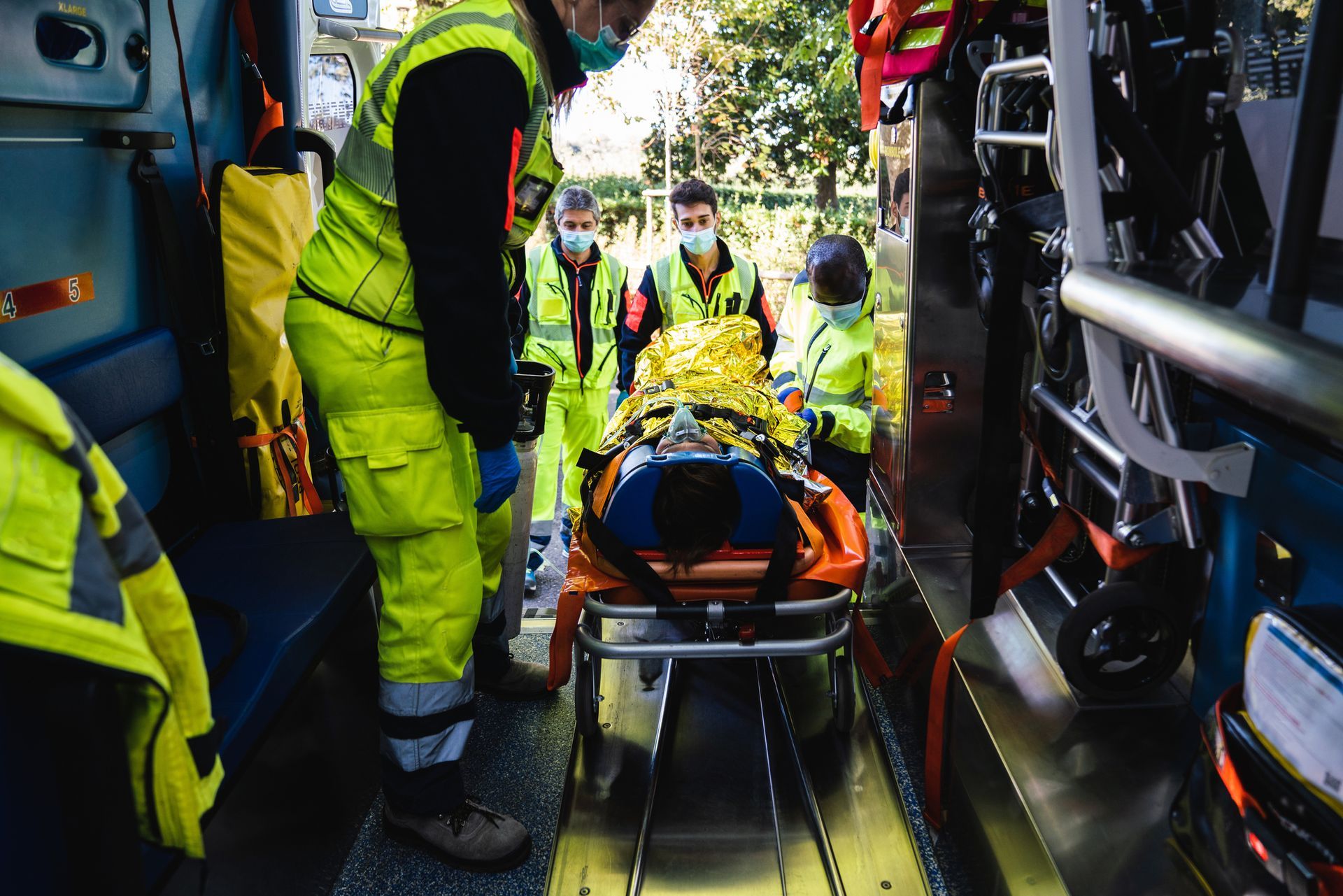 Un gruppo di paramedici sta caricando un paziente su una barella e lo sta caricando su un'ambulanza.