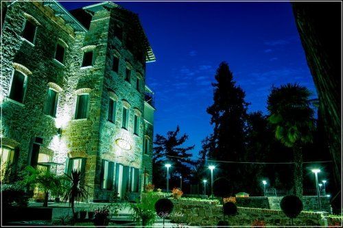 Vista notturna di edificio in pietra illuminato con giardino adiacente