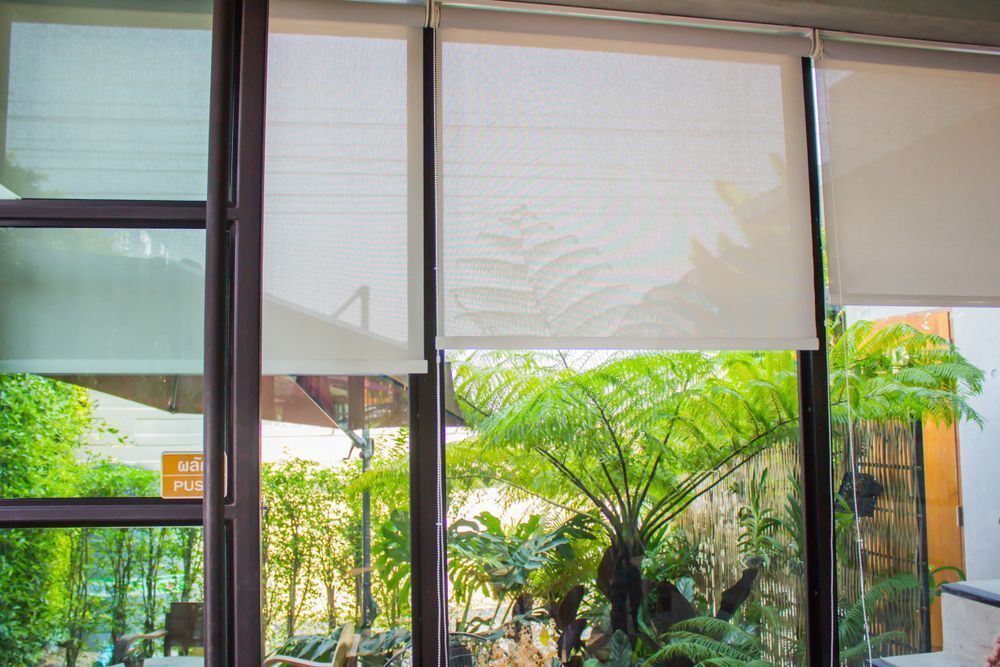 A Window With Blinds on It and a View of a Garden — Curtain Haven & Blinds in Laurieton, NSW