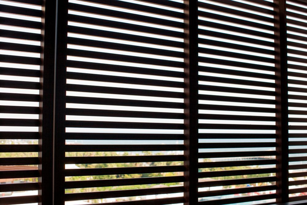A Close Up of a Window With Wooden Blinds on It — Curtain Haven & Blinds in Laurieton, NSW