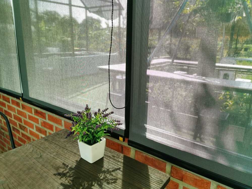 A Potted Plant is Sitting on a Table in Front of a Screened in Porch — Curtain Haven & Blinds in Harrington, NSW