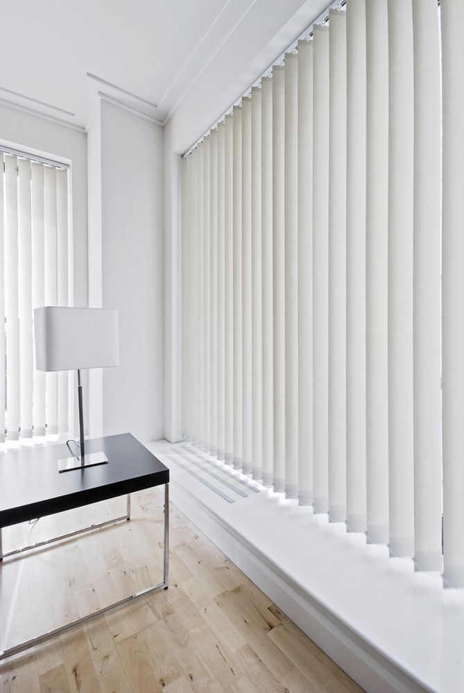 A Living Room With White Vertical Blinds and a Black Table — Curtain Haven & Blinds in Harrington, NSW