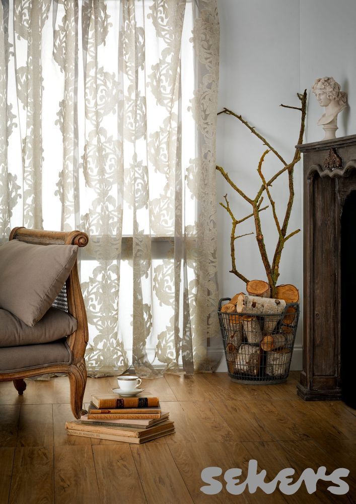 A Living Room With a Chair and a Fireplace and a Stack of Books on the Floor — Curtain Haven & Blinds in Laurieton, NSW