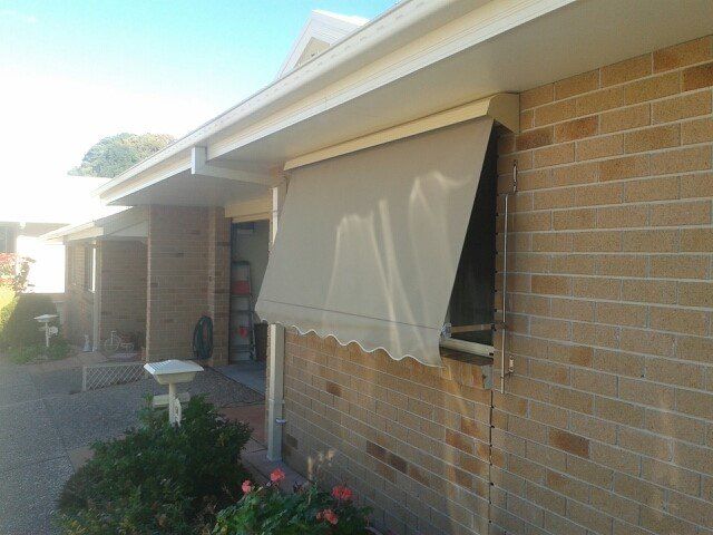 A Brick House With a Window Awning on It — Curtain Haven & Blinds in Laurieton, NSW
