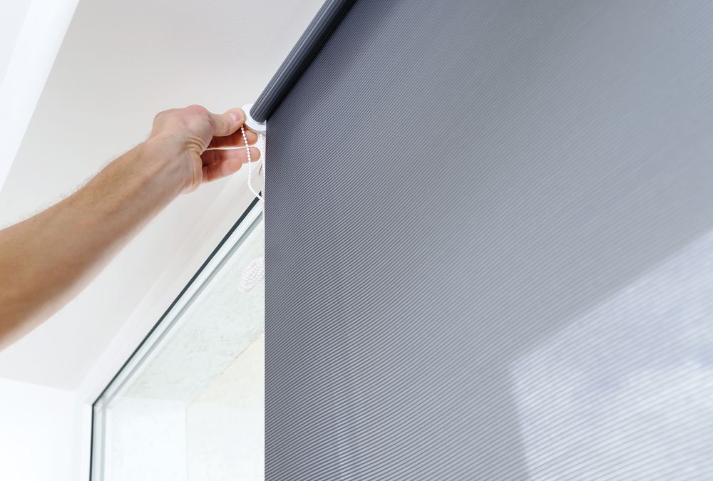 A Person is Adjusting a Roller Blind on a Window — Curtain Haven & Blinds in Laurieton, NSW