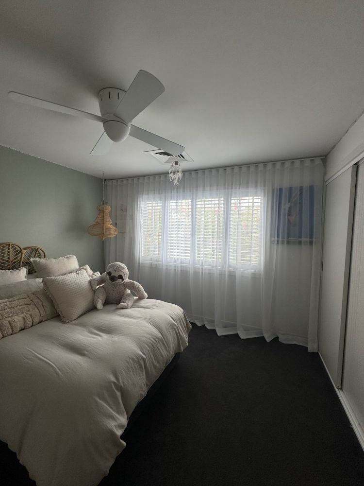 A Bedroom With a Bed and a Ceiling Fan — Curtain Haven & Blinds in Laurieton, NSW