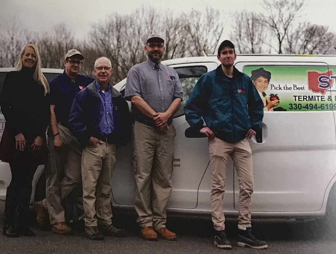 A group of people are posing for a picture in front of a white van.