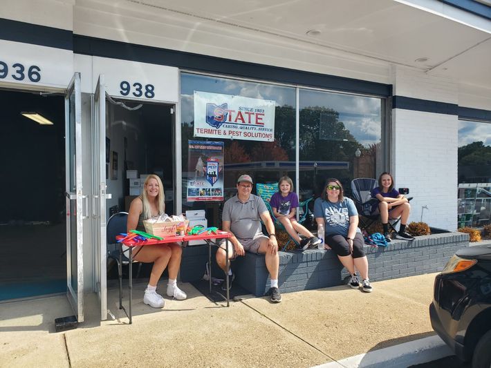 A group of people are sitting outside of a store.