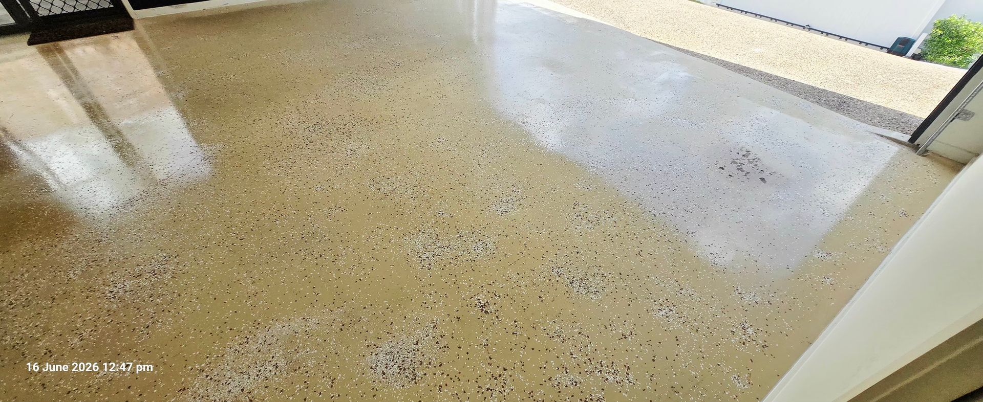Speckled beige floor or patio surface with a light doorway and walls at the edges