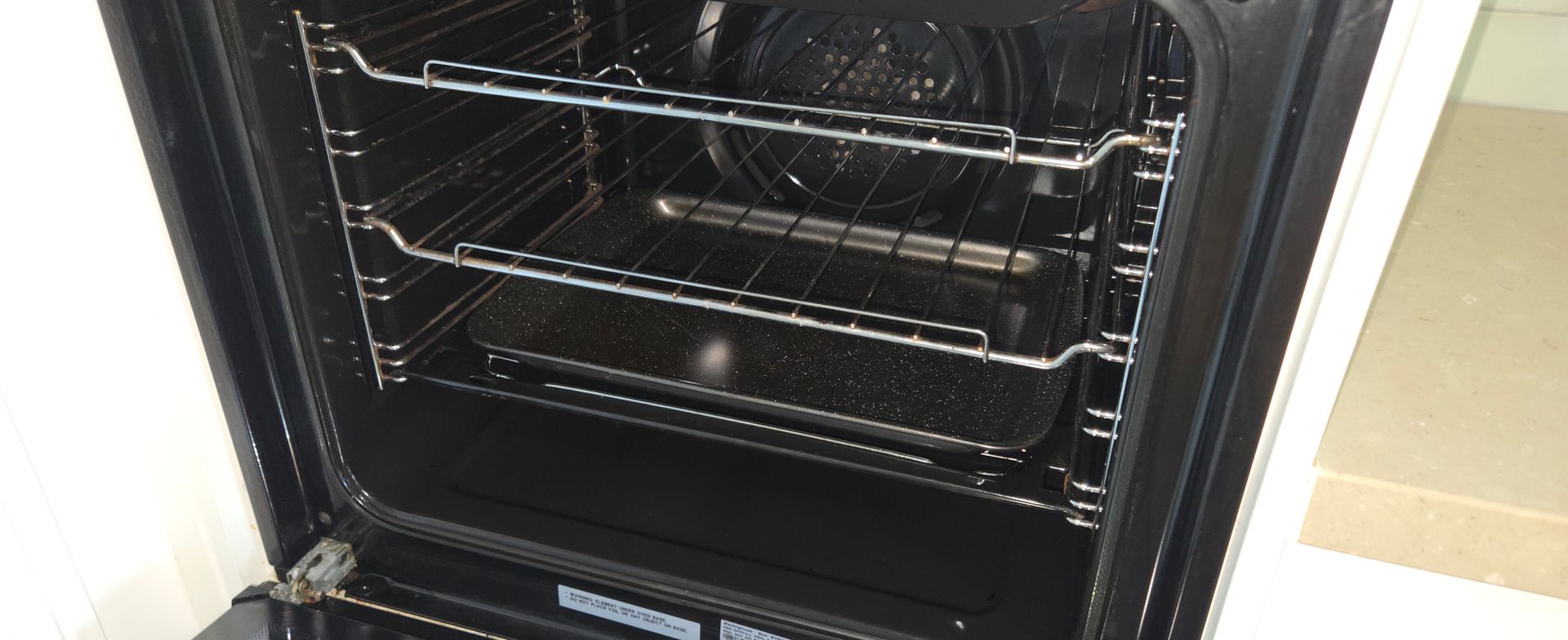 Open oven interior with metal racks and a dark door frame