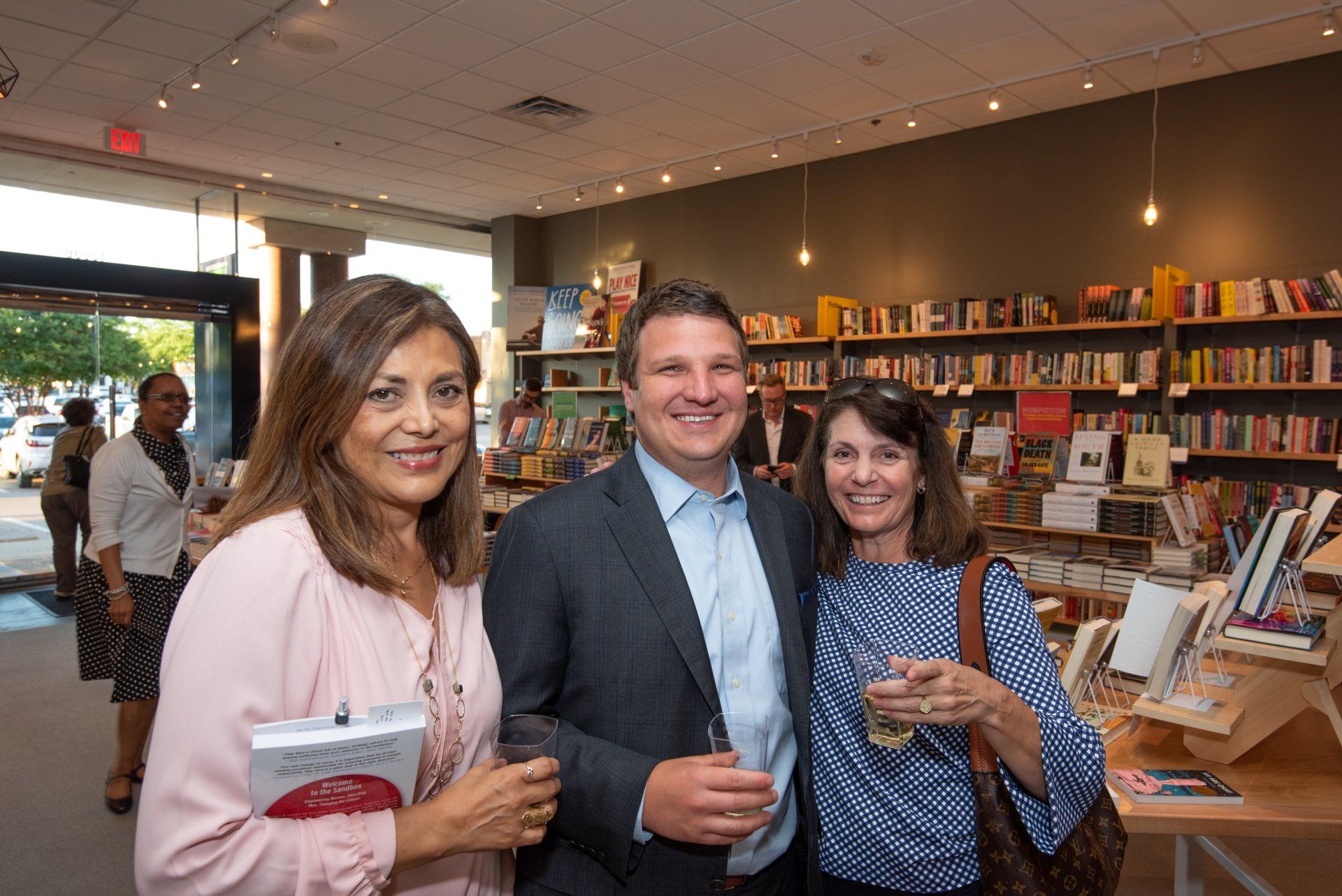 A man and two women are posing for a picture in a bookstore.