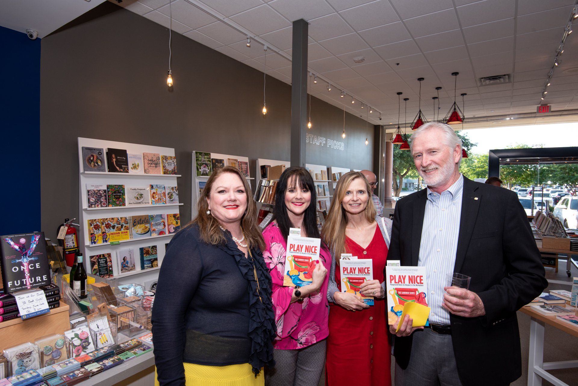 A group of people standing next to each other in a store holding books.