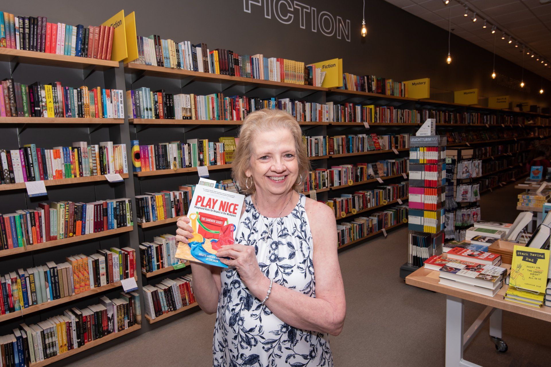A woman is holding a book in a bookstore.