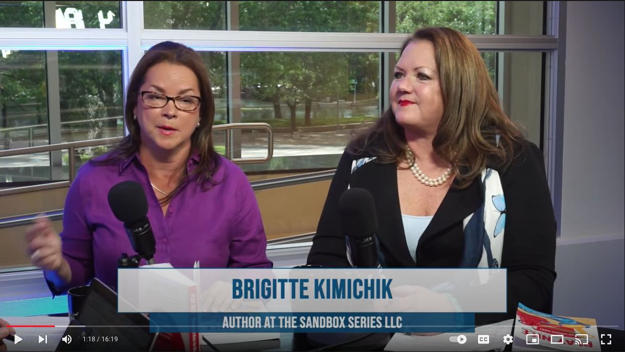 Two women are sitting at a table with microphones in front of them.