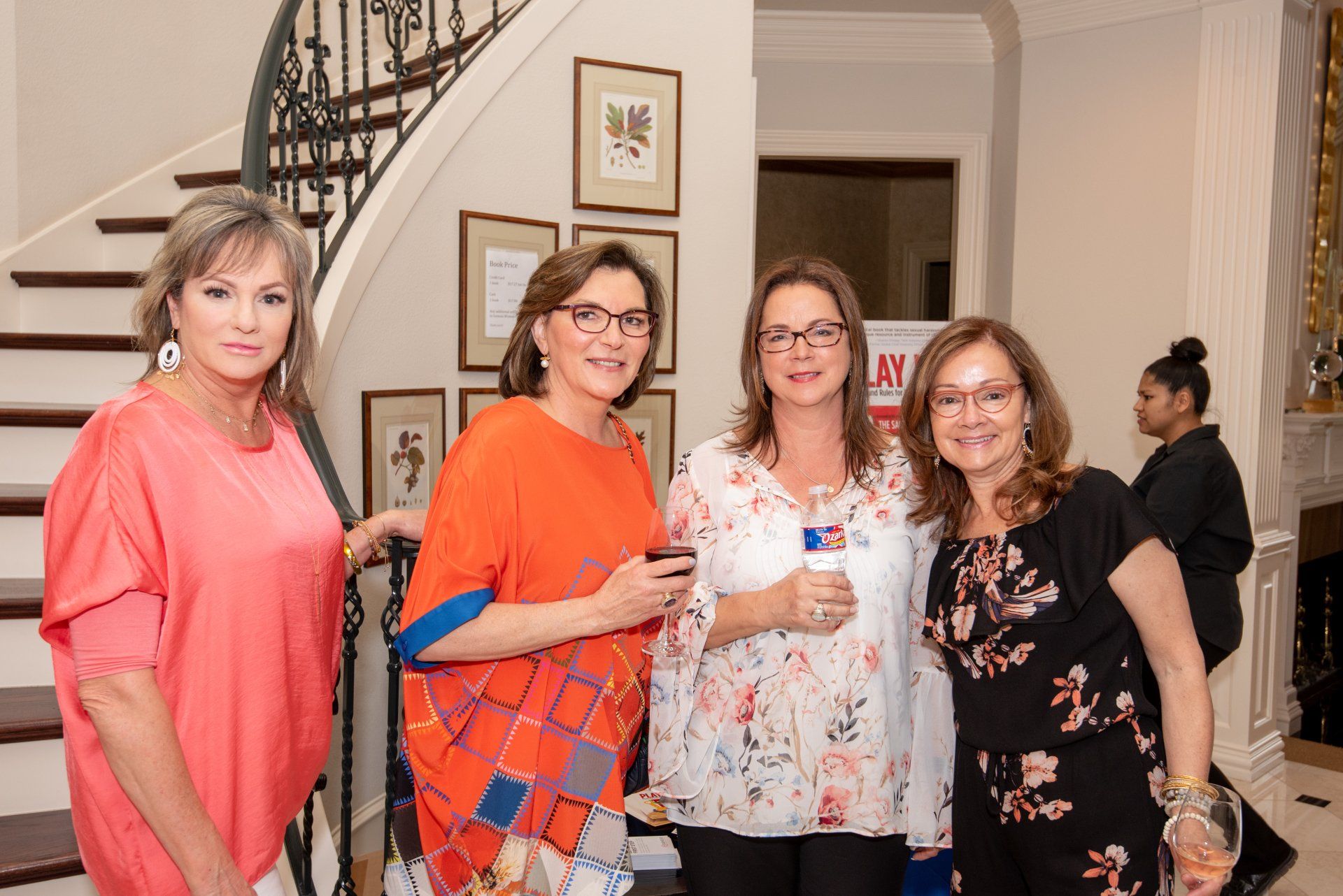A group of women are posing for a picture in front of a staircase.