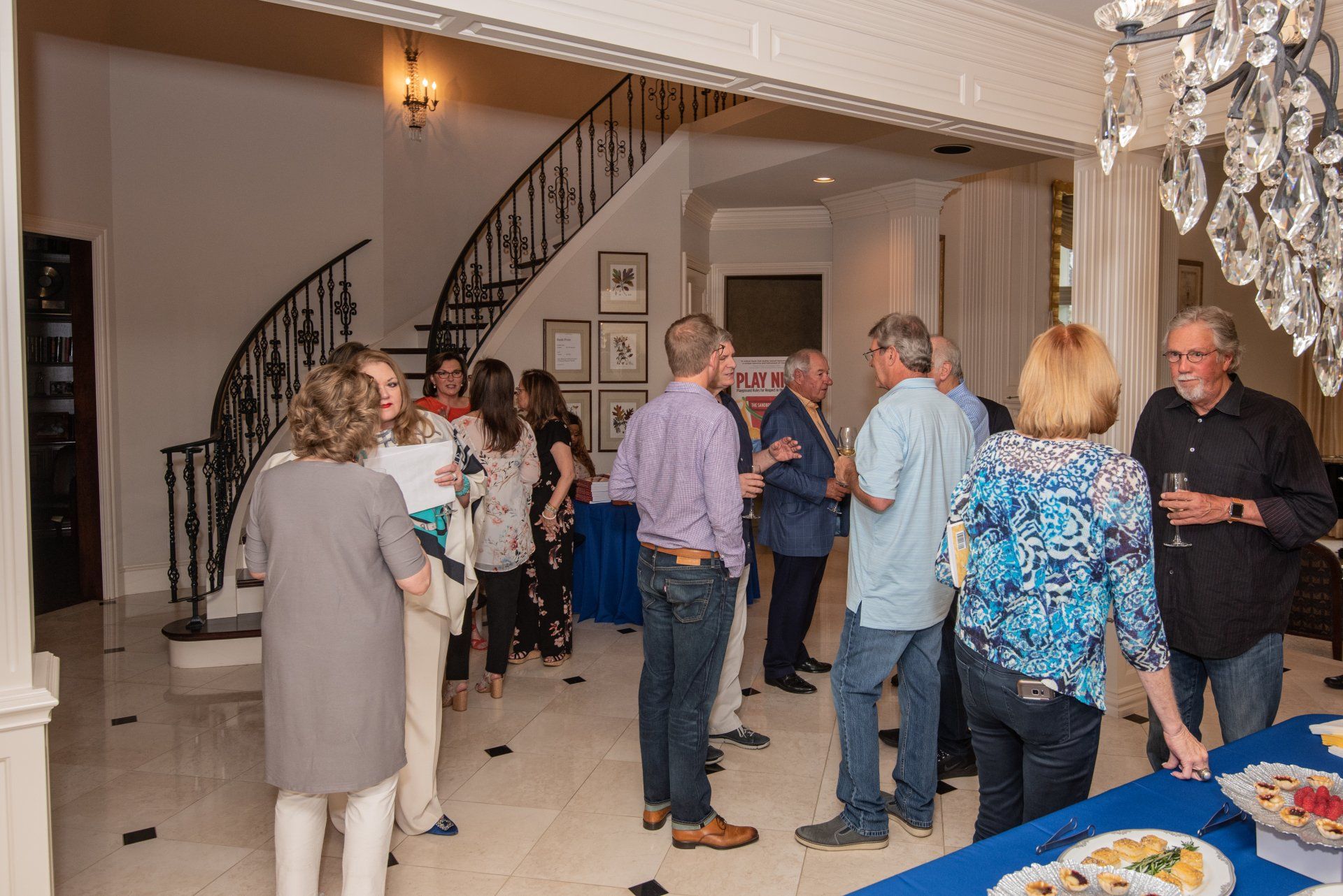 A group of people are standing in a room talking to each other.