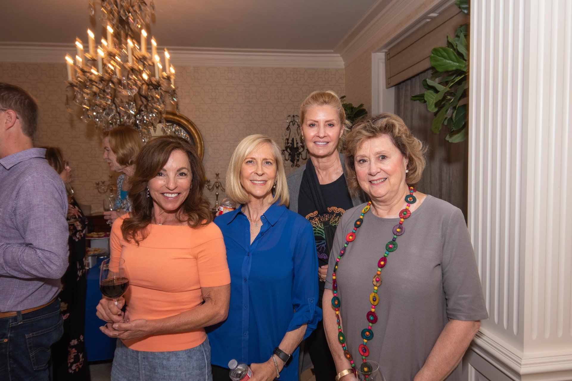 A group of women are posing for a picture in a room with a chandelier in the background.