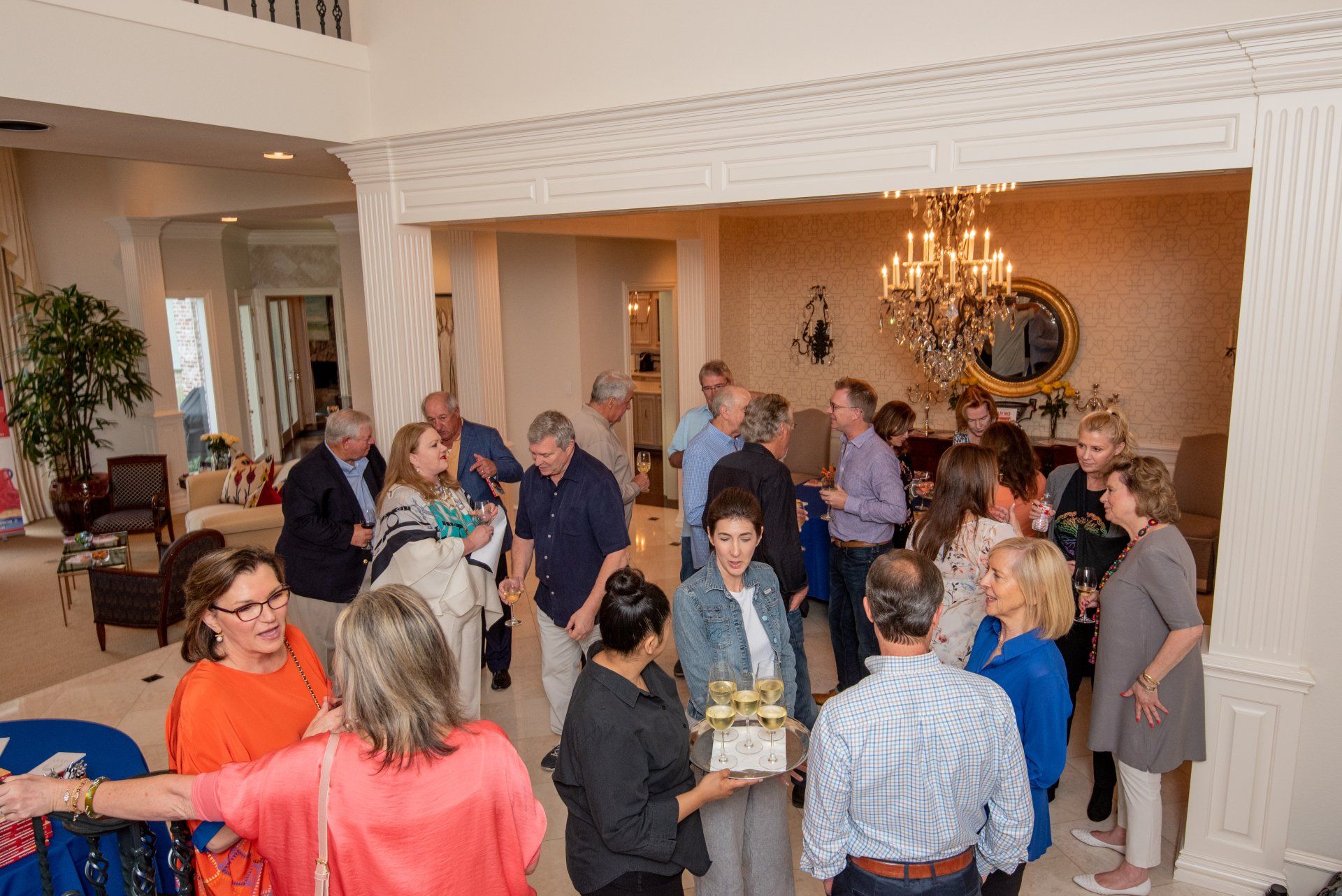 A group of people are standing in a room talking to each other.