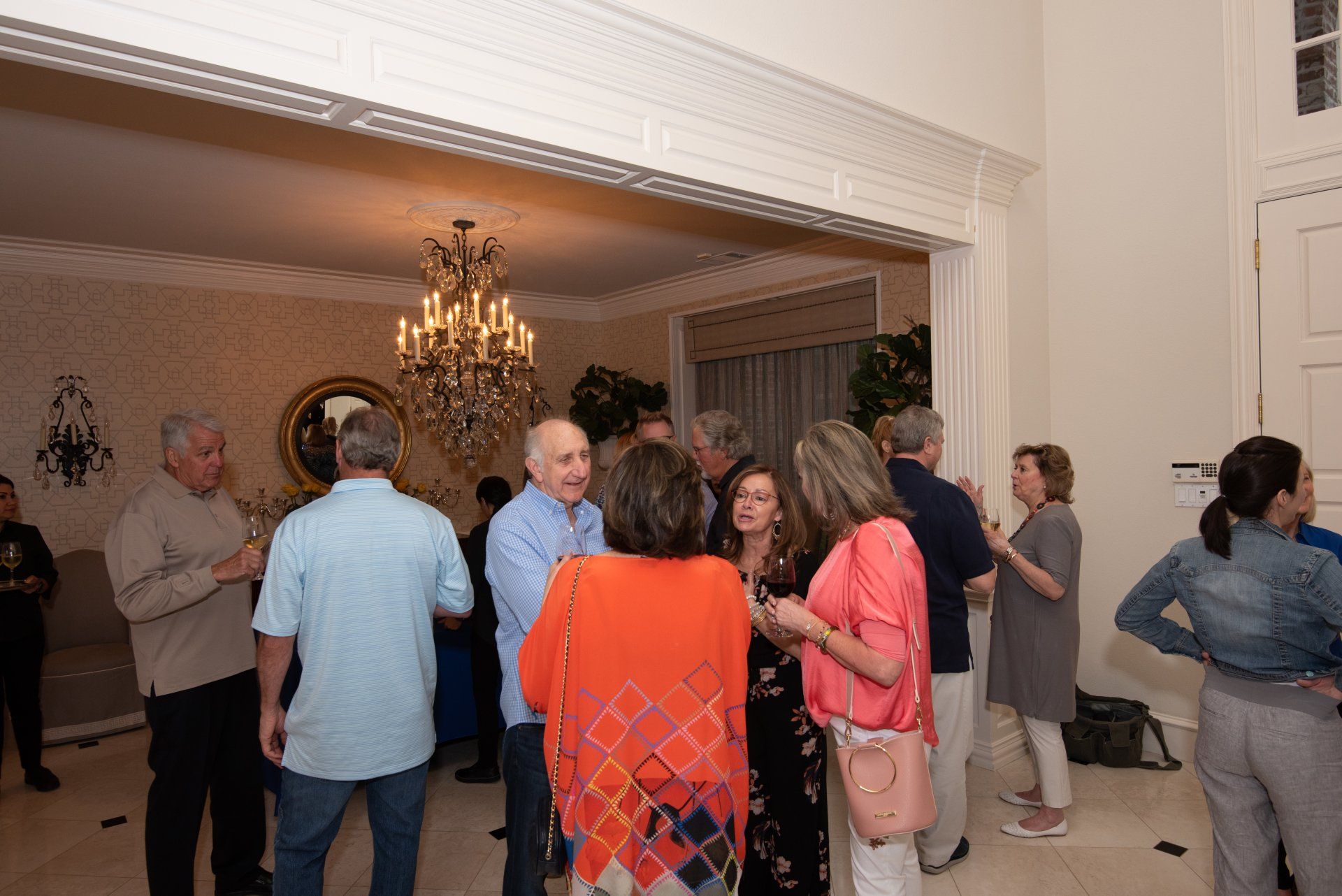 A group of people are standing in a room talking to each other.