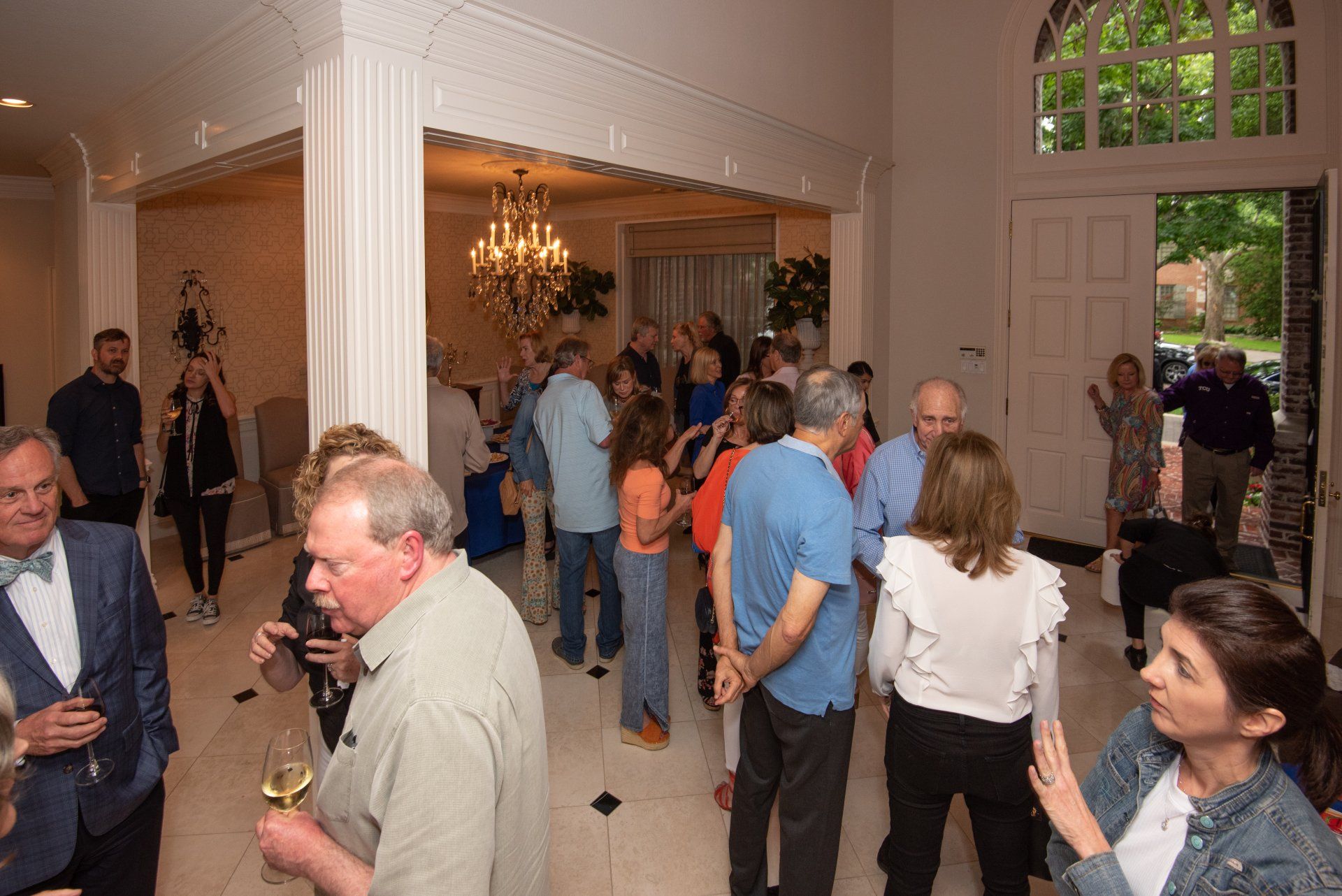A group of people are standing in a room talking to each other.