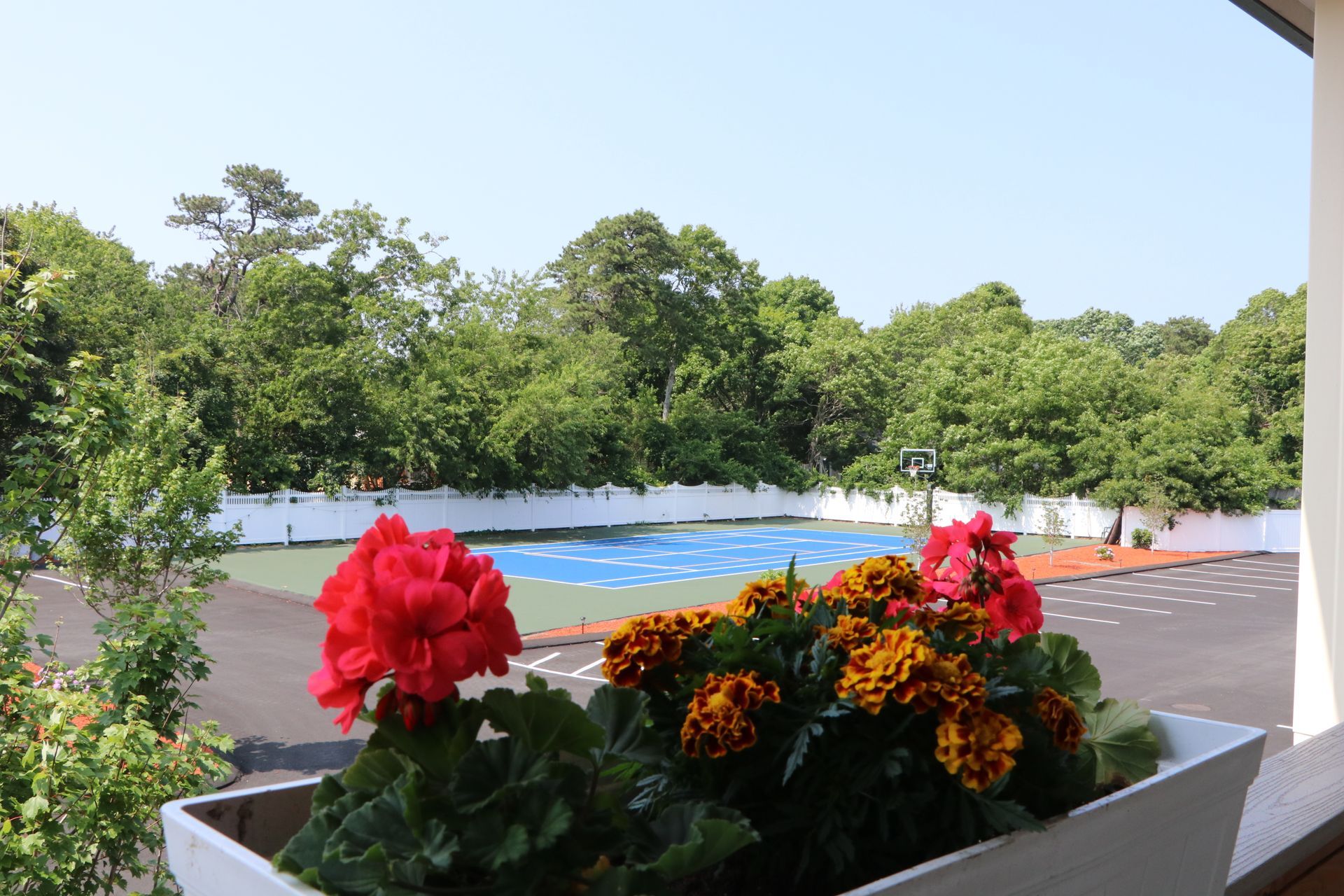 A planter box with red and orange flowers in front of a blue and green playground.