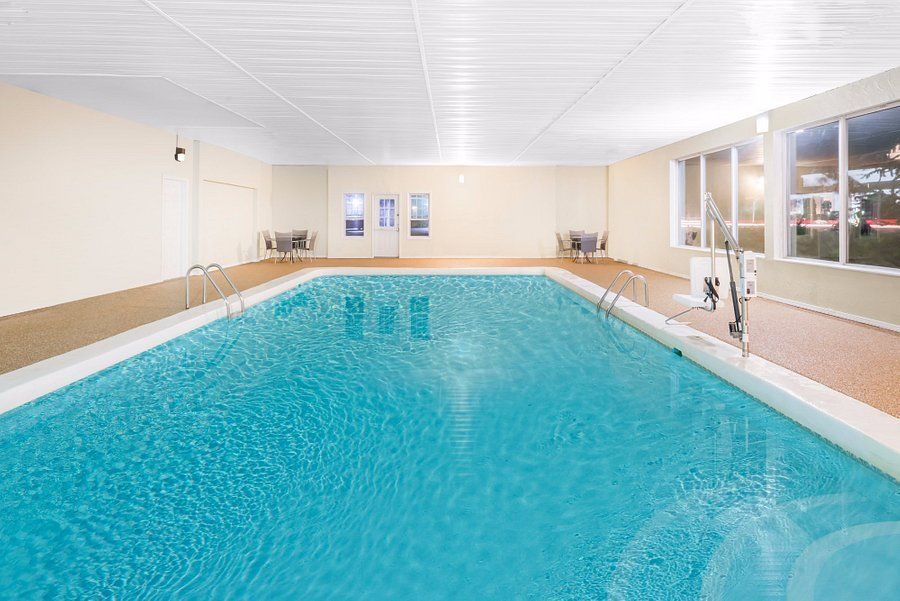 Indoor swimming pool with light blue water, surrounded by beige walls and a tiled deck.