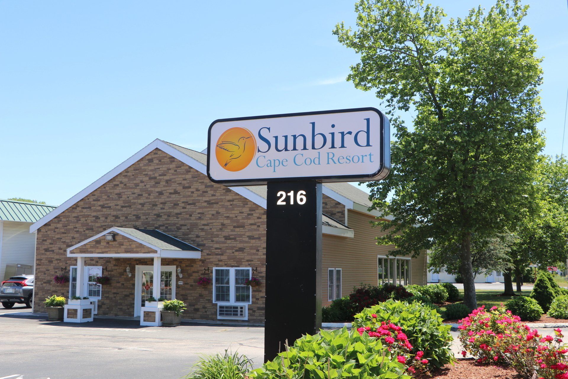 Sunbird Cape Cod Resort building with sign, sunny day.