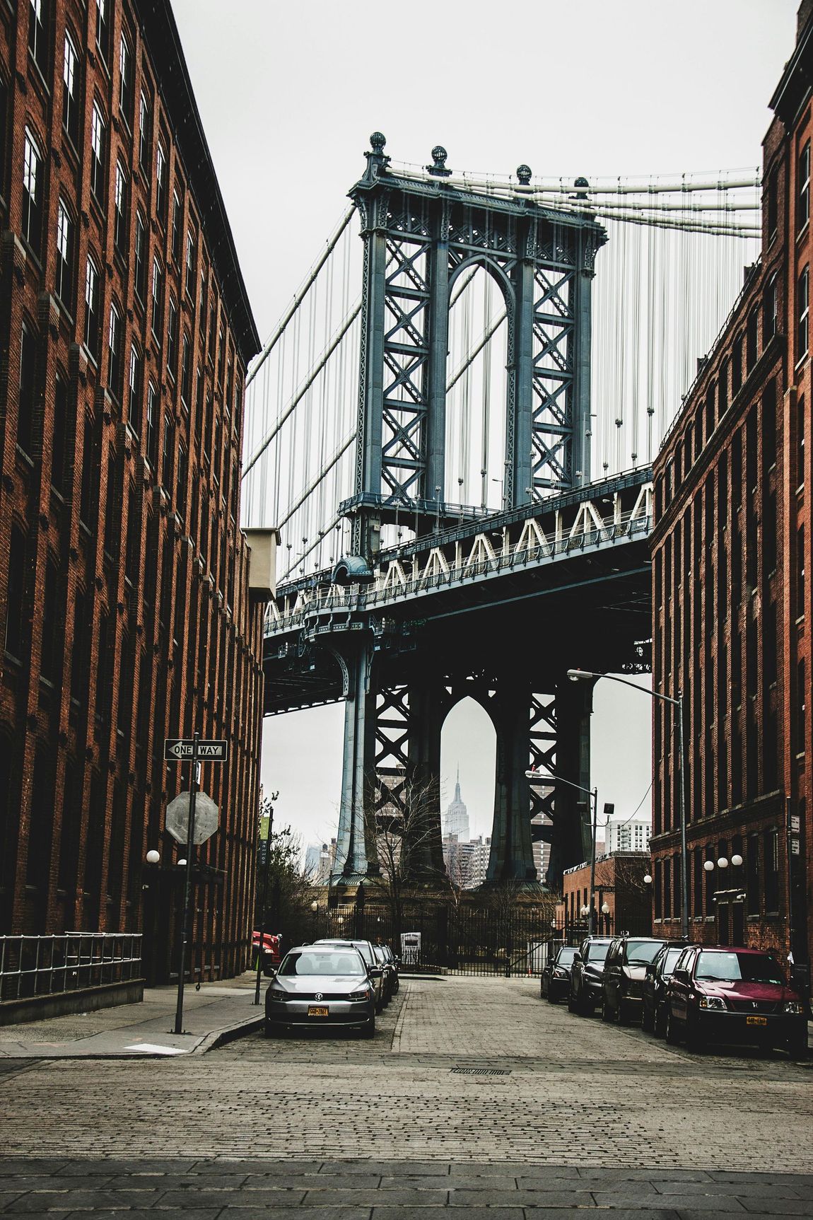 A bridge between two buildings with cars parked underneath it