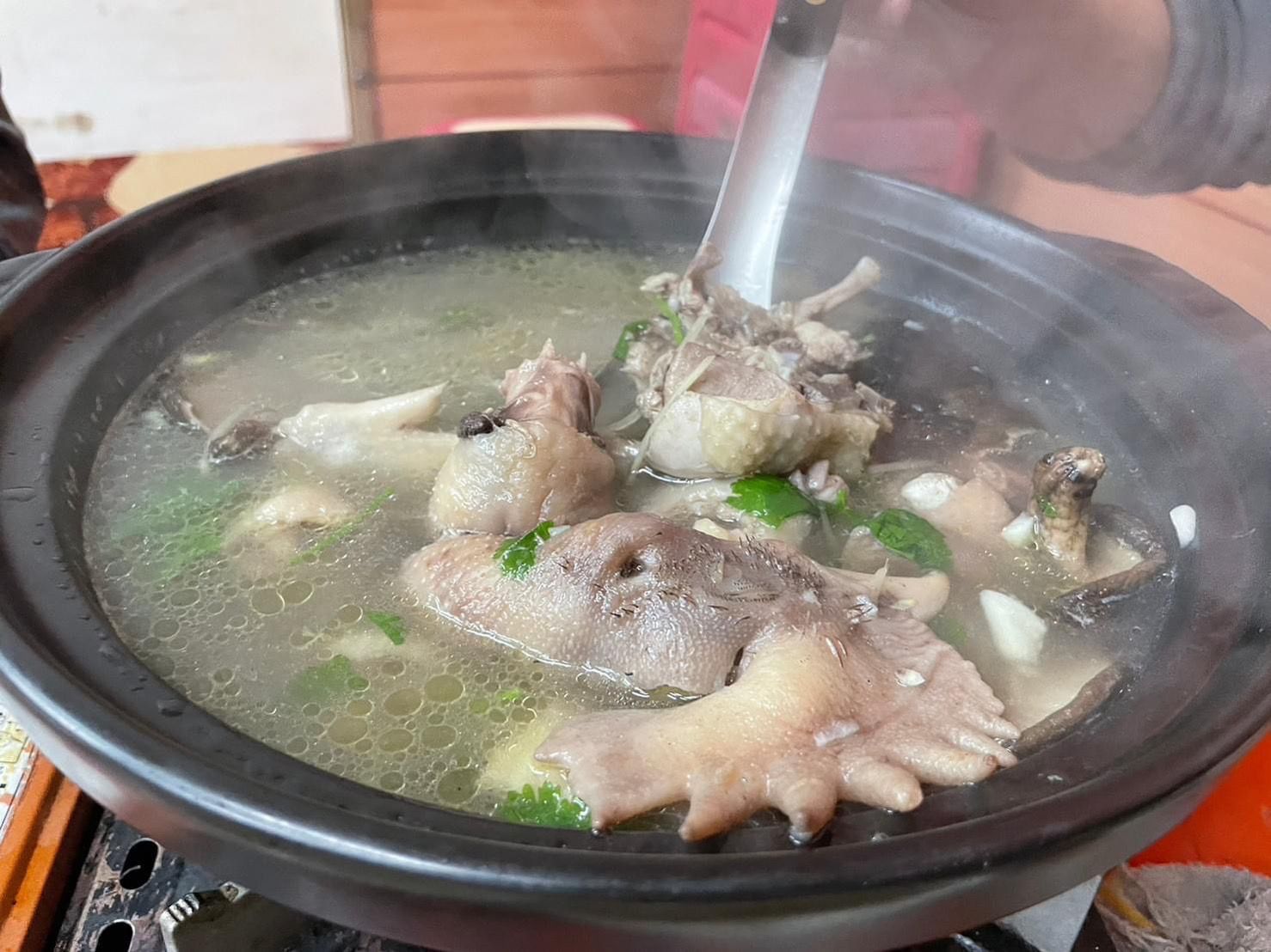 中興紅羽1982土雞烤雞放在盤子裡,周圍擺放著綠葉;其他菜餚在背景中。