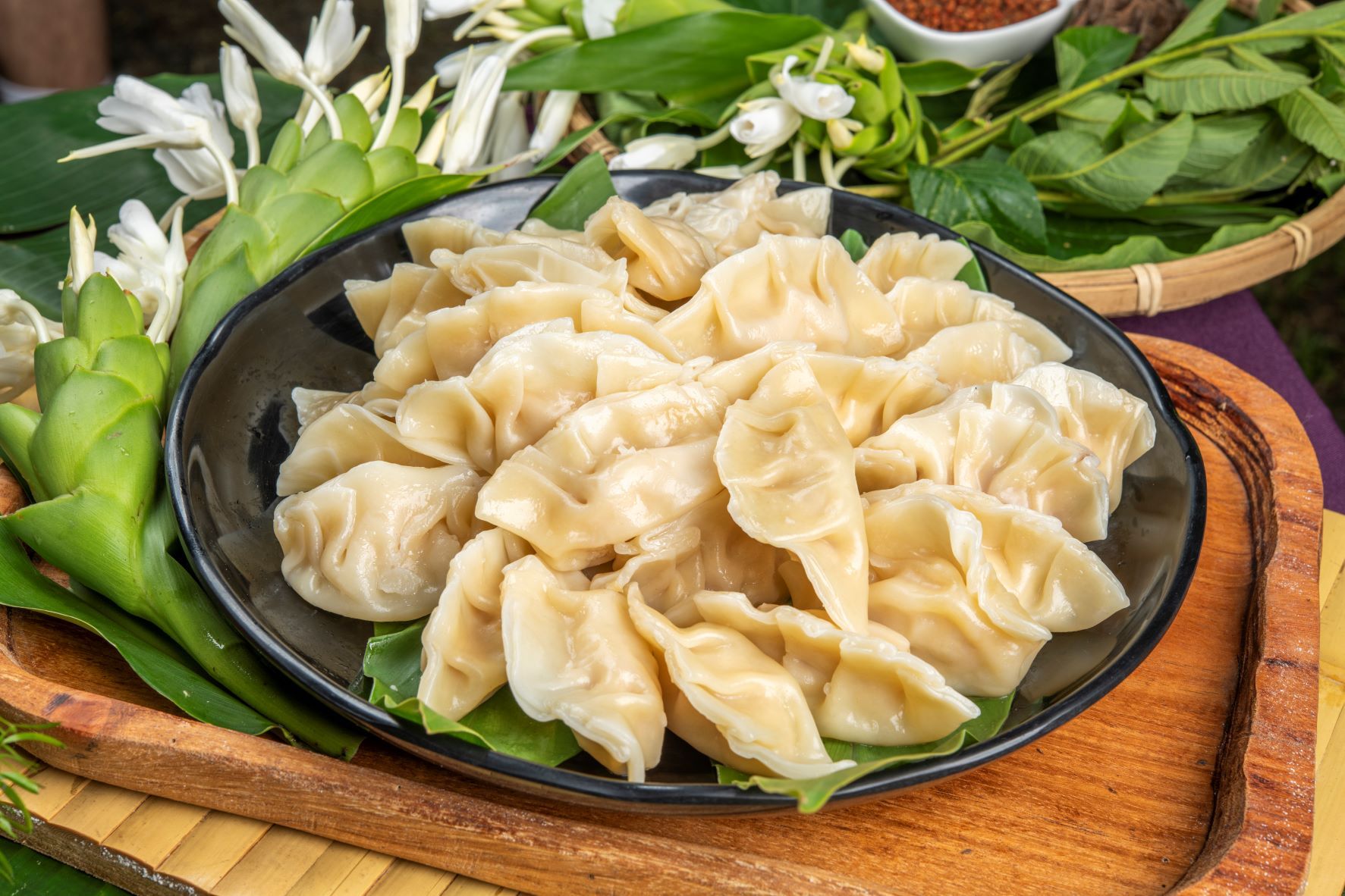 一盤中興紅羽土雞胸肉做成的香雞餃,周圍點綴著綠葉,放在木托盤上。