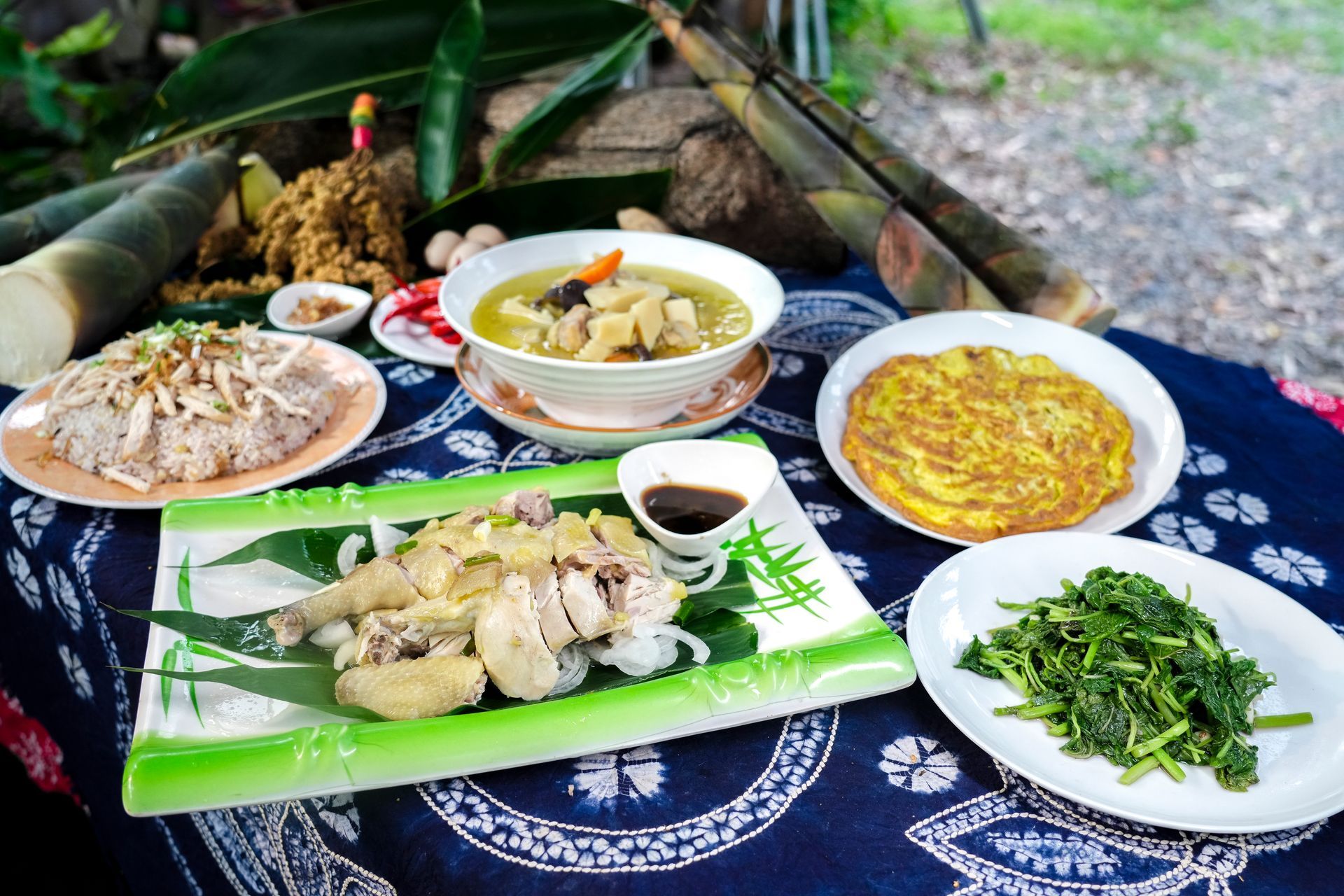 戶外擺放著一張桌子，上面擺放著各種中興紅羽1982土雞菜餚，包括湯和蛋捲。