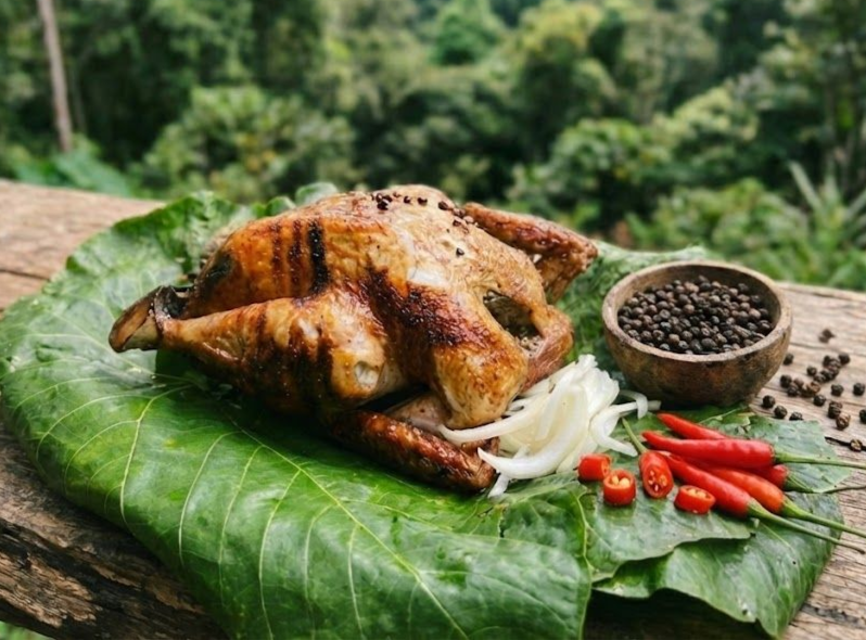 中興紅羽1982土雞,製作的烤雞放在一片大綠葉上,配上洋蔥和一小碟醬汁。