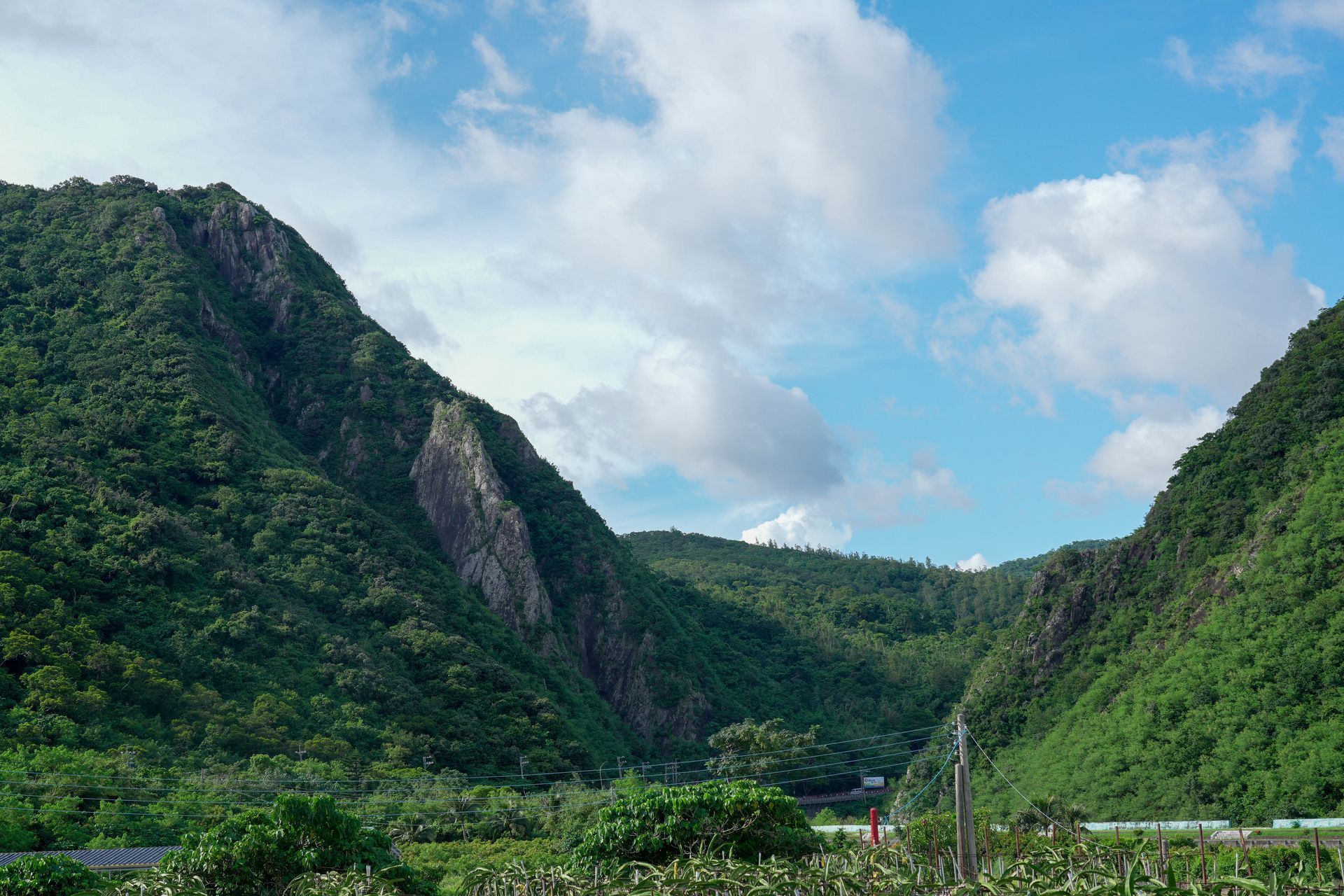 青山在多雲的藍天下,山間有一條山谷。