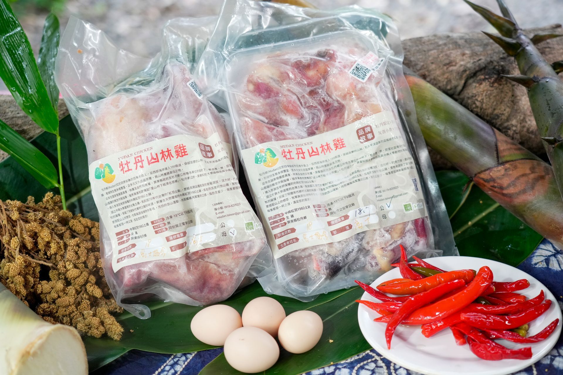 桌上擺放著包裝好的中興紅羽1982土雞肉、雞蛋、紅辣椒和竹筍，周圍點綴著綠植。