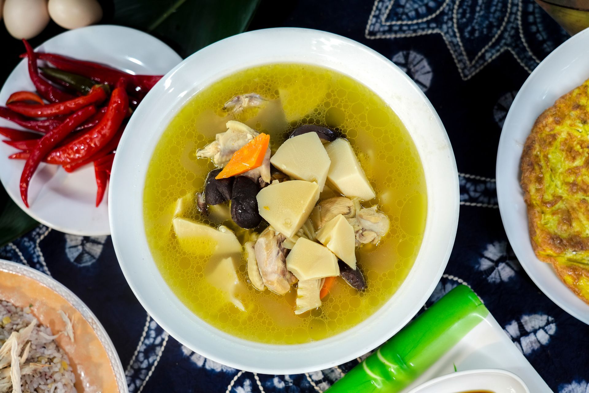 中興紅羽土雞的雞湯裡有當季鮮筍、胡蘿蔔和蘑菇,盛在白色碗裡。