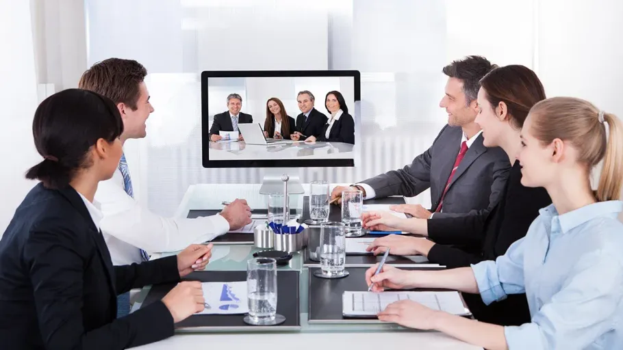A group of people are sitting around a table looking at a computer screen.