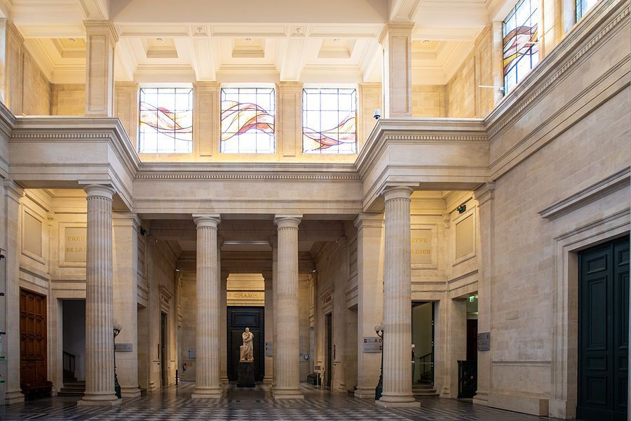A large hallway in a building with columns and stained glass windows.