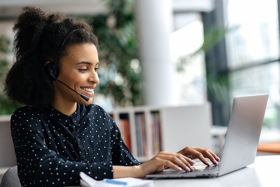 A woman wearing a headset is using a laptop computer.