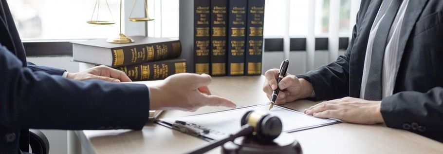 Two lawyers are sitting at a table signing a document.