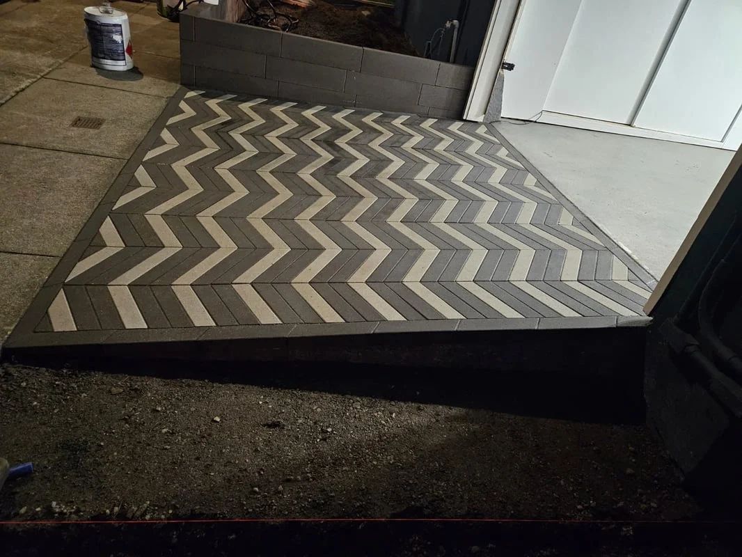 Chevron-patterned outdoor rug on a porch beside a doorway and a paint can.