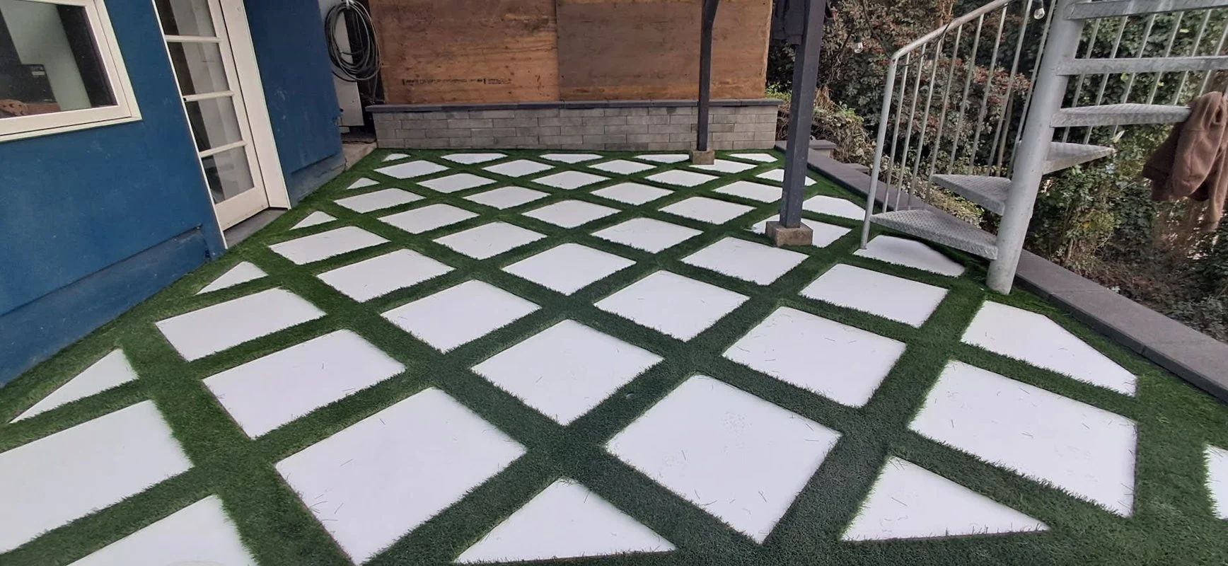 Green-and-white checkered patio with square stepping stones and white railing on the right