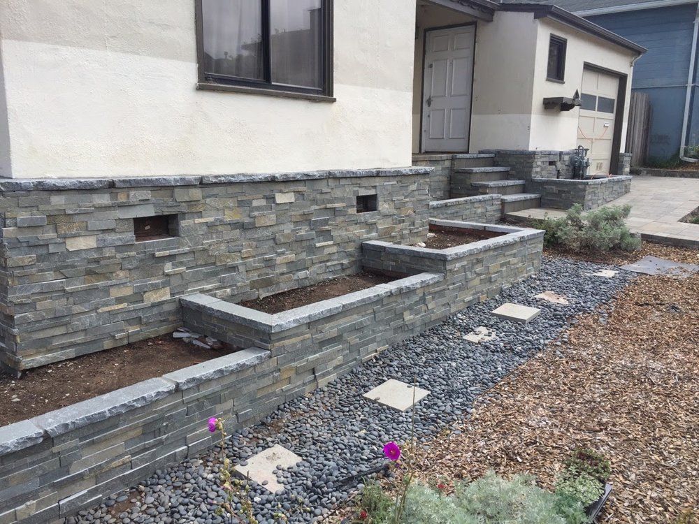 Front yard stone retaining walls with gravel, steps, and a house exterior Front yard stone retaining walls with gravel, steps, and a house exterior