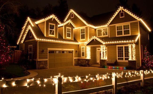 A house is decorated with Christmas lights and a fence.