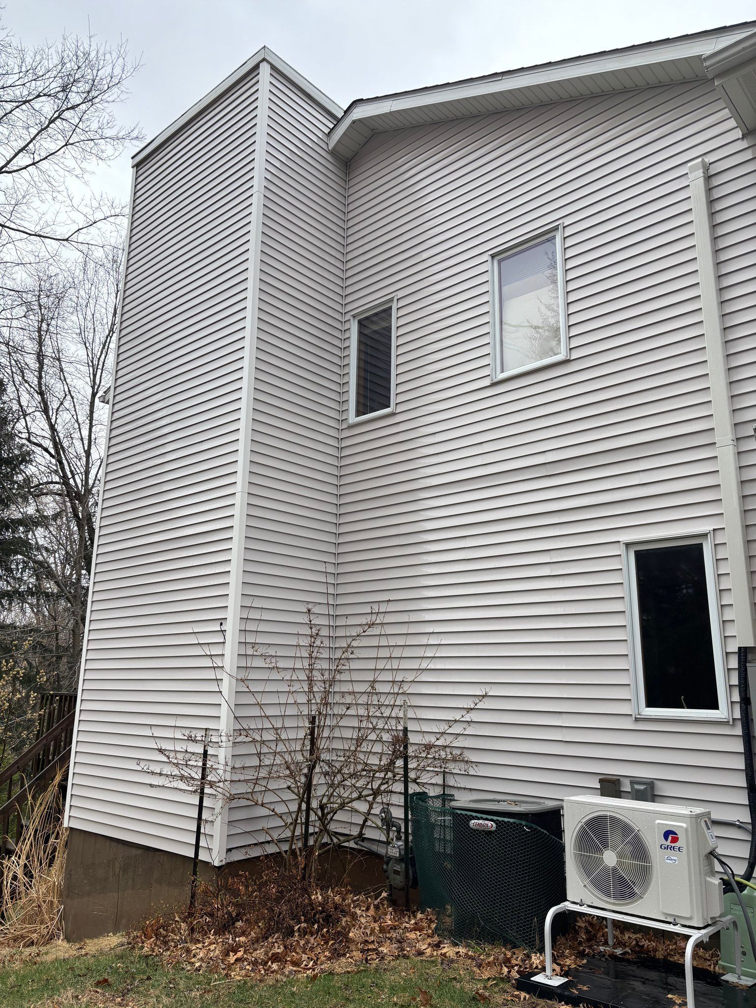 A man is sitting on the roof of a house with a ladder.