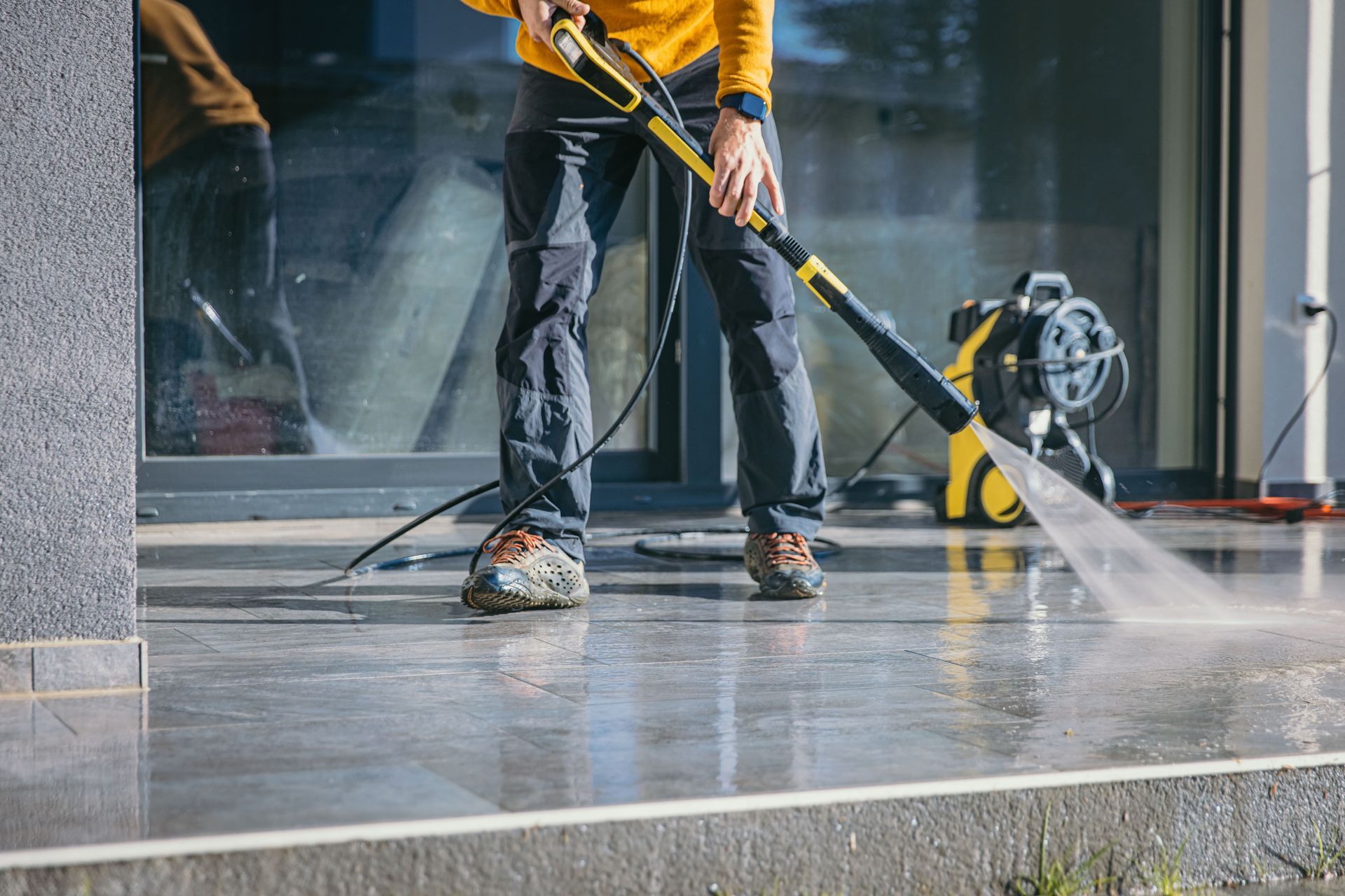 A man is using a high pressure washer to clean a concrete floor.