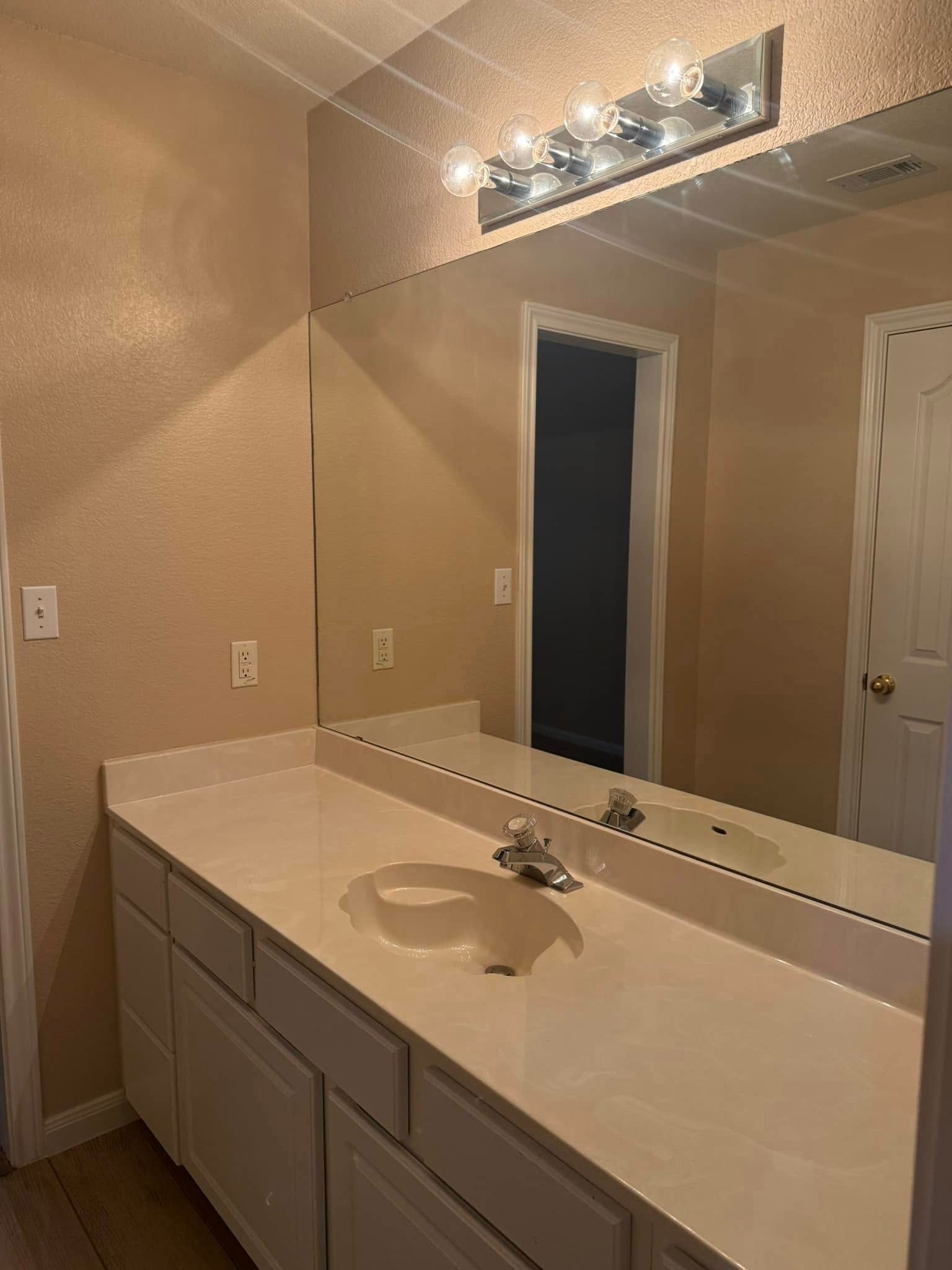 A bathroom with a sink and a large mirror.