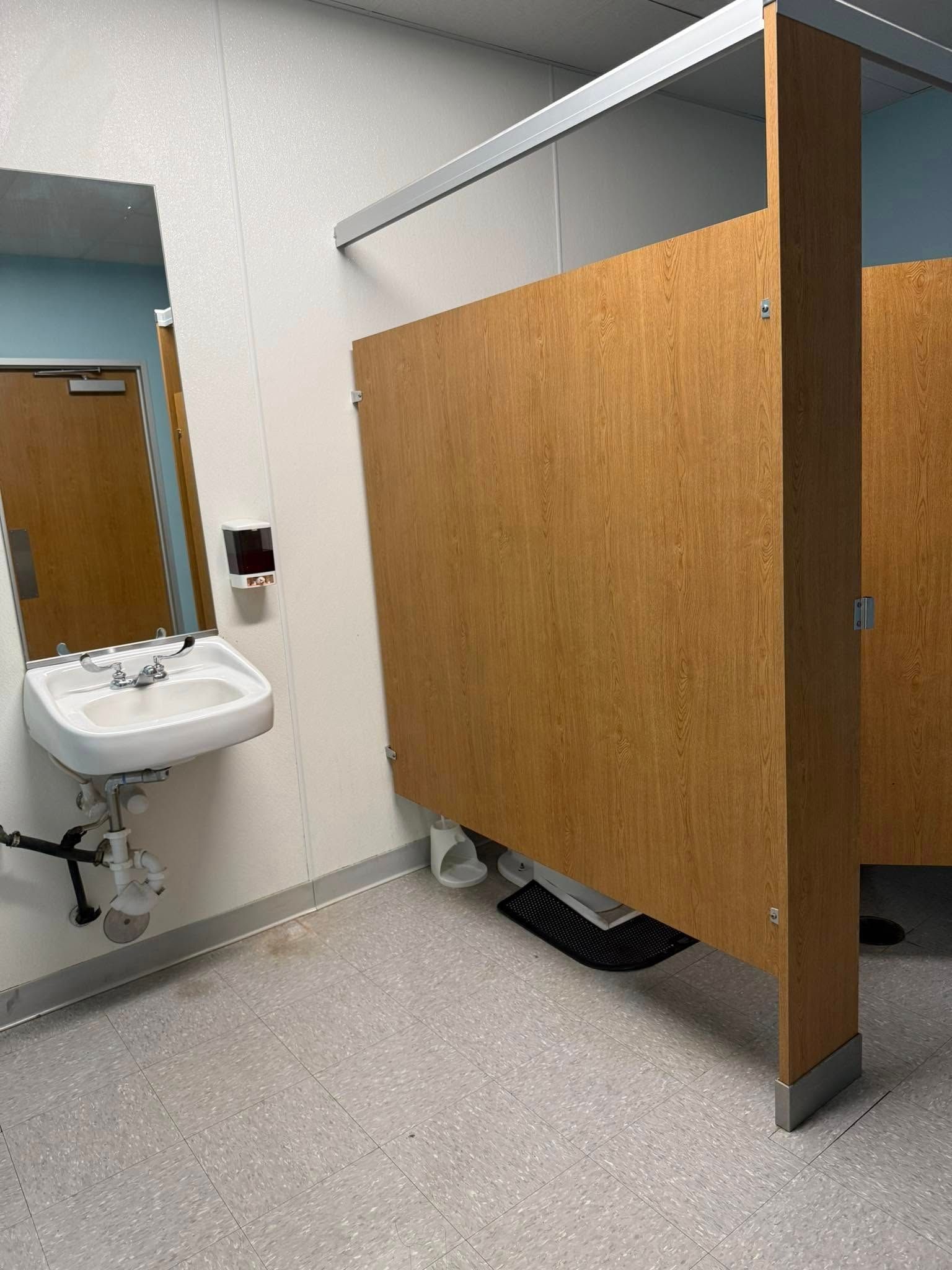 A bathroom with a sink and a wooden divider