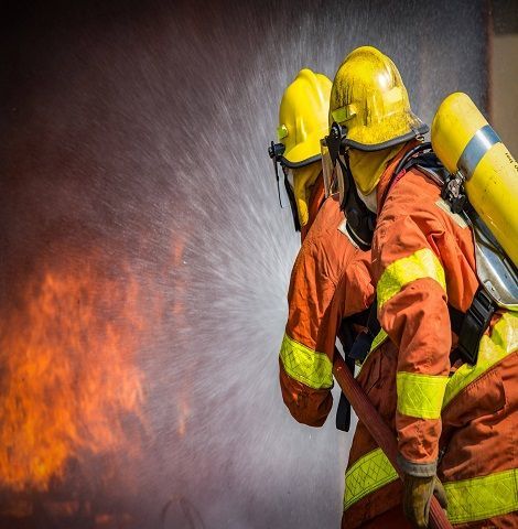 Two firefighters are spraying water on a fire with a hose.
